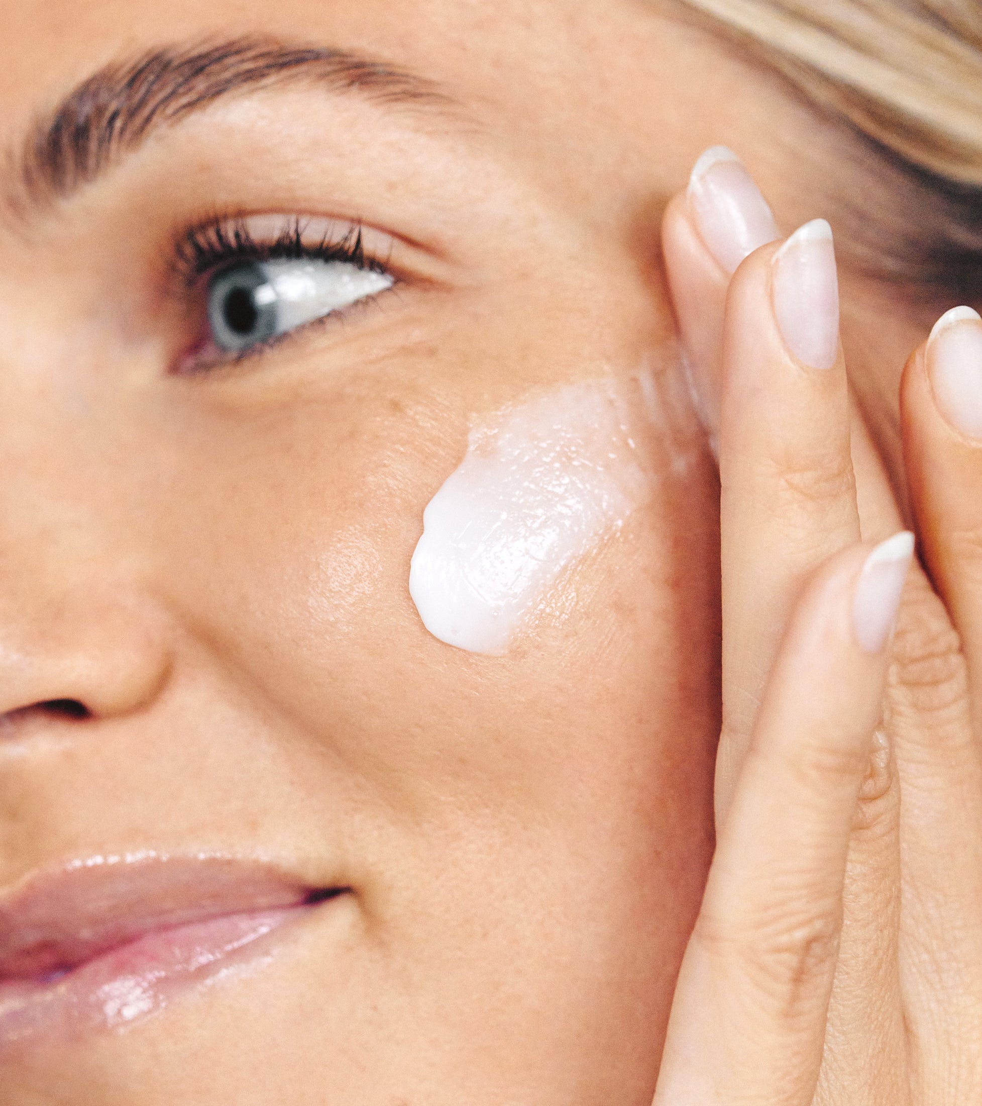 Closeup of a model swiping Daily Moisturizer across her cheek with her fingertips. 