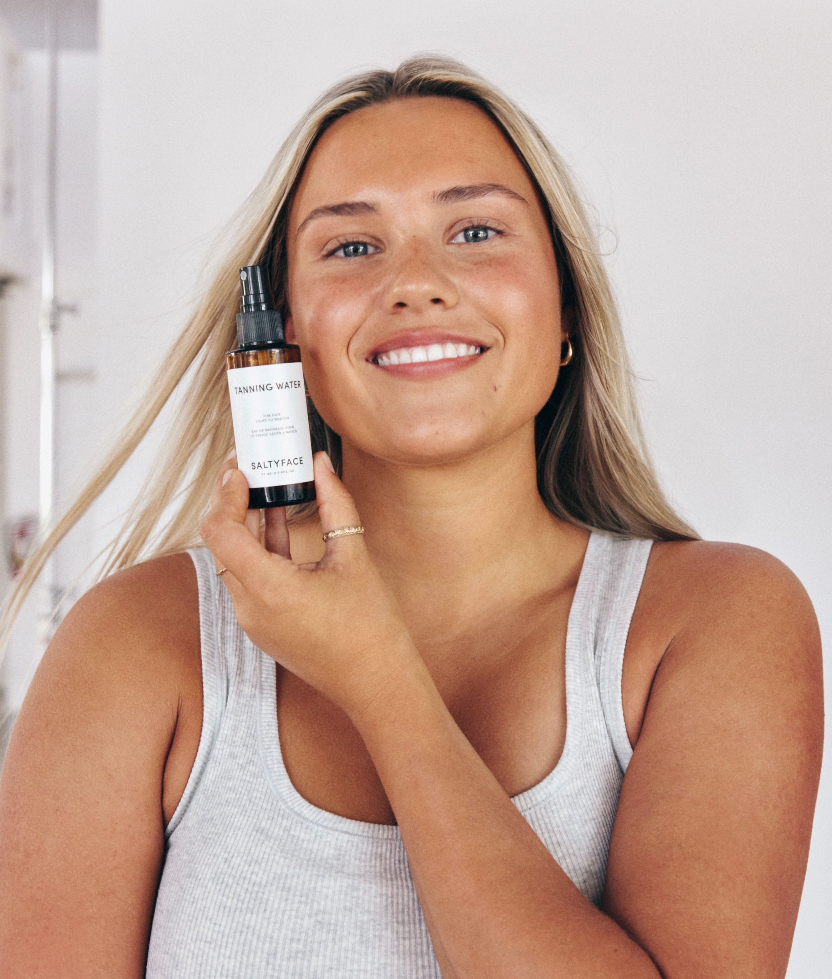 Model holding Saltyface Tanning Water with the Mist Top. 