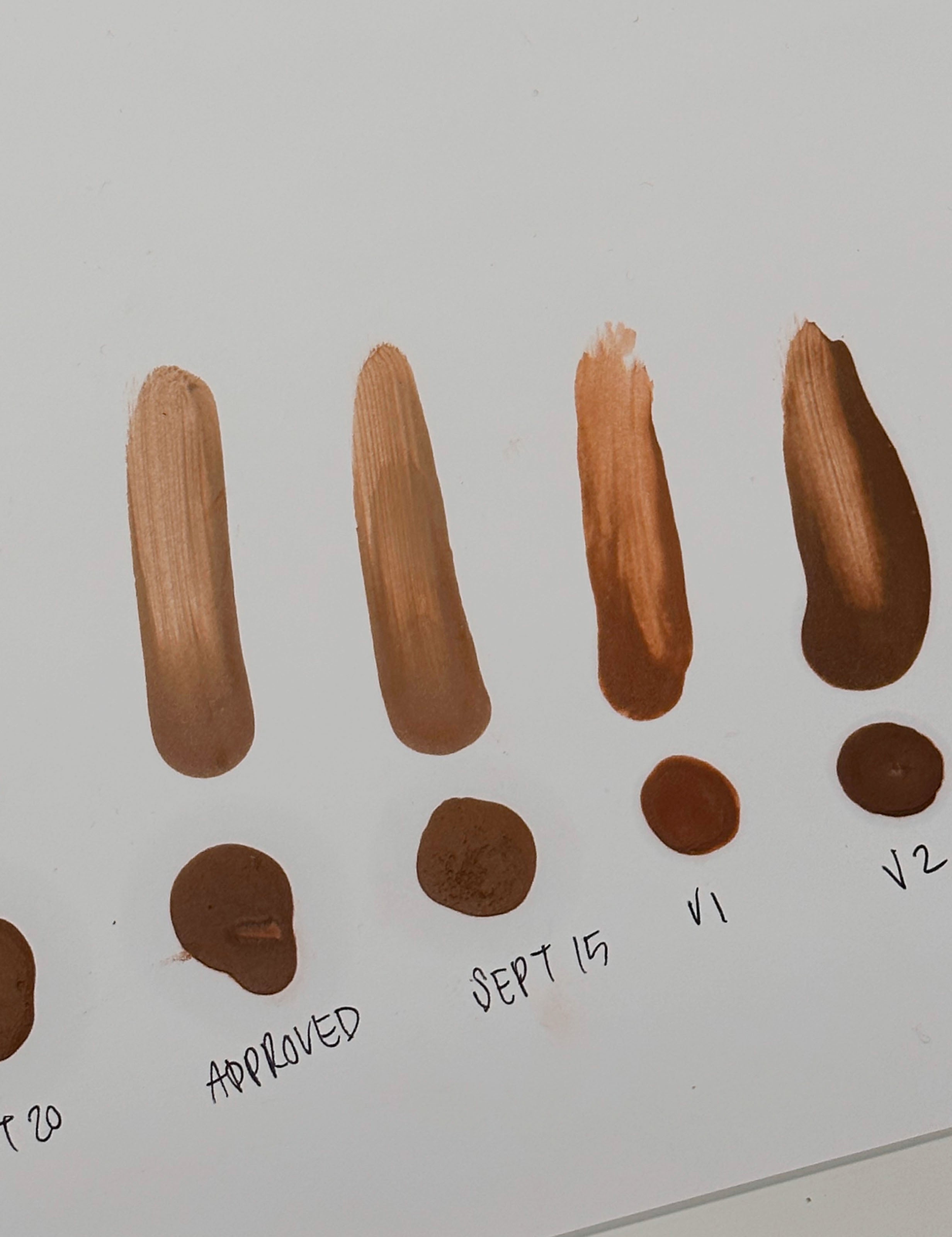 Various test swatches of Liquid Bronzer are shown spread across a white piece of paper. 